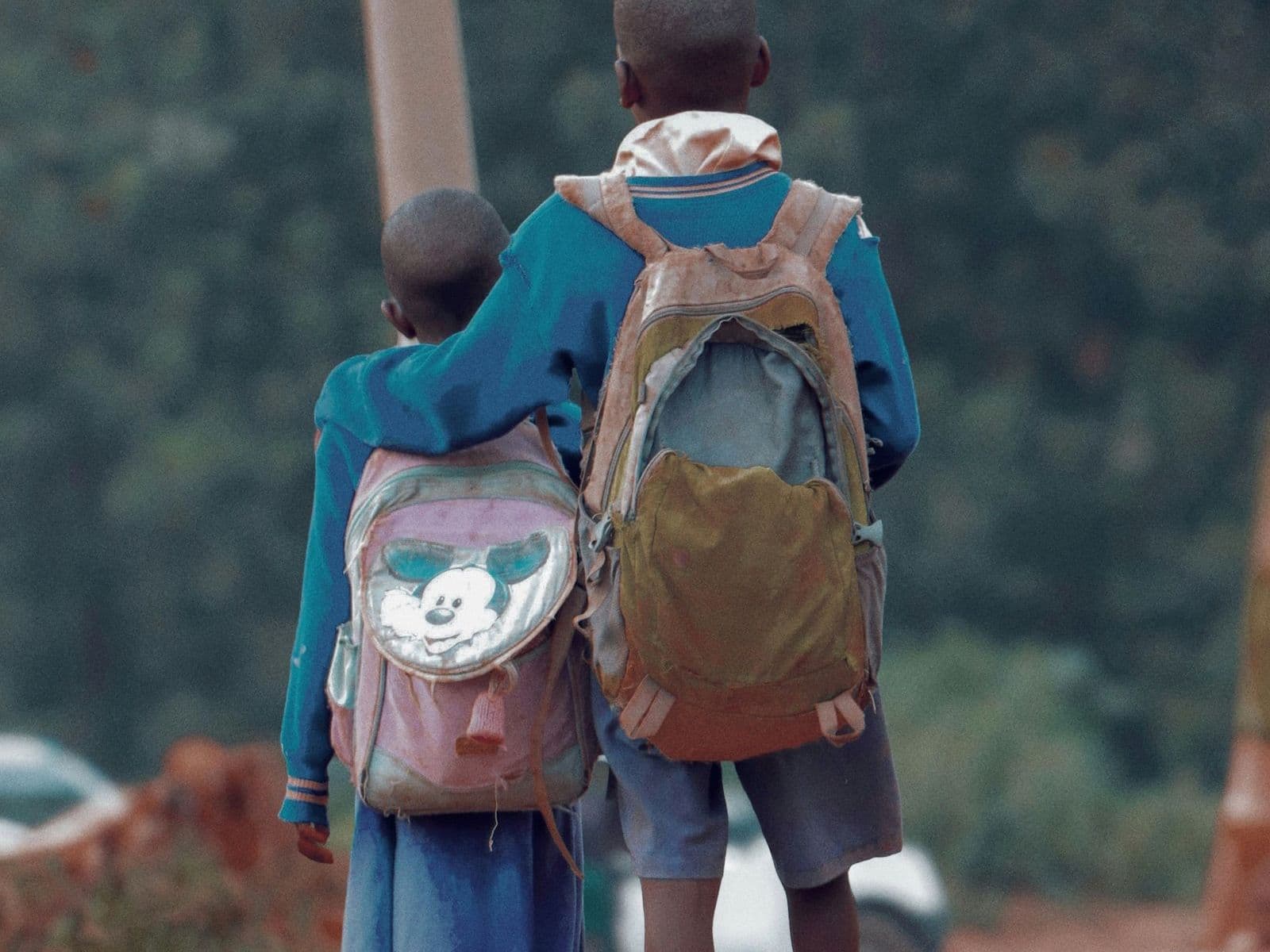 Two pupils with backpacks walking to school, seen from behind